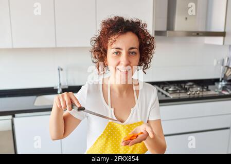 Woman pointing at some carrots with a knife. High quality photo. Stock Photo
