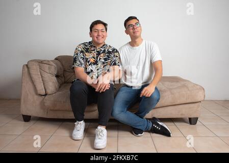 male couple sitting in their empty living room happy looking at the horizon Stock Photo