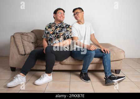 male couple sitting in their empty living room happy looking at the horizon Stock Photo