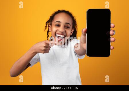 Black girl showing blank empty smartphone screen and pointing Stock Photo