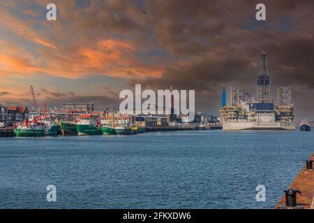 Vissershaven, IJmuiden, The Netherlands, March 24, 2021: Various green-hulled ships and oil rig moored at the Trawlerkade in the outer harbor of IJmui Stock Photo