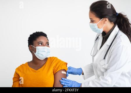 African female getting vaccine against Covid-19 on white background Stock Photo