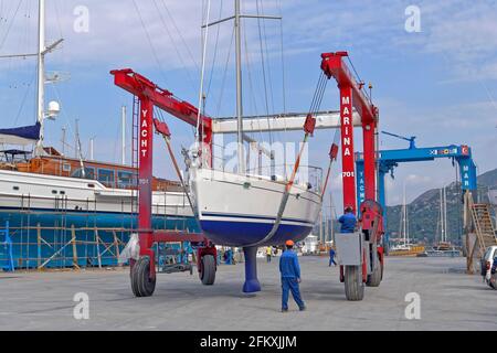 Cruising yacht being lifted and moving towards launching pool. Stock Photo