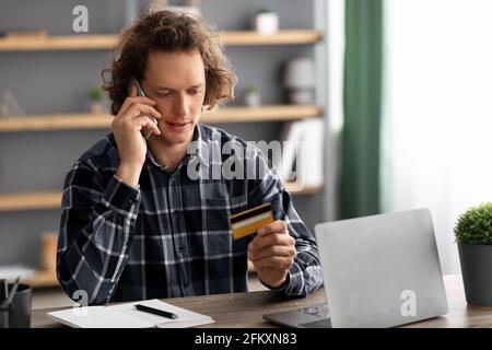 Man Calling To Bank Holding Credit Card Having Problem Indoors Stock Photo