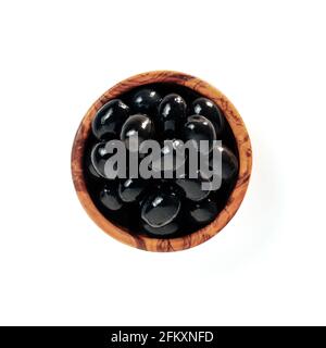 Small wooden bowl with black olives isolated on white background. Flat lay or top view of small beautiful olive tree bowl with full black olives, isolated with clipping path Stock Photo