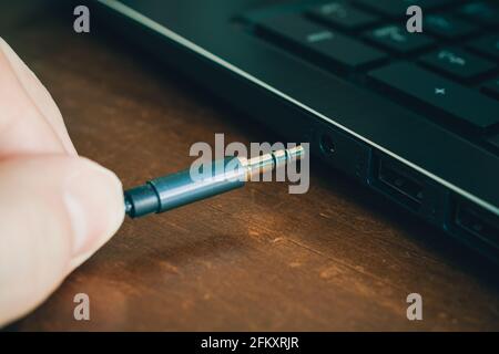 Hand Inserts Headphone Cable In Headphone Jack Of A Notebook Stock Photo
