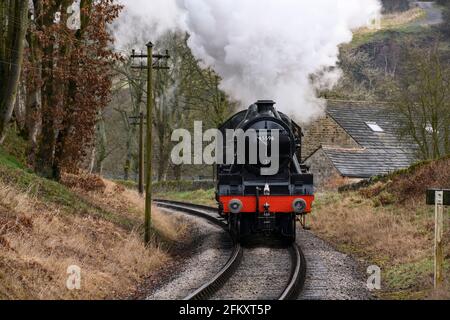 Historic steam train (loco) coming round bend in track, puffing smoke clouds travelling on scenic rural heritage railway - KWVR, Yorkshire England UK. Stock Photo