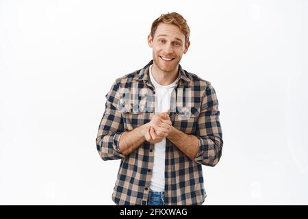 Image of hopeful redhead man smiling, rub hands and asking for favour, begging for help, need something, lending money, standing over white background Stock Photo
