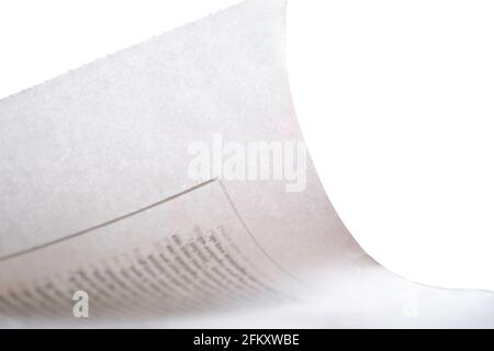 Folded corner of the slightly translucent paper of a newspaper with illegible text on white background. Shallow depth of field. Copy space Stock Photo
