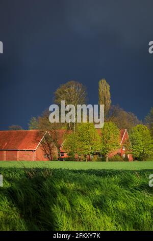 Haltern, NRW, Germany. 04th May, 2021. Dark, thundry clounds hang over a farm in the small town of Haltern in NRW, whilst the sun breaks through for a moment. A day of strong winds, rain and sunny spells, as storm Eugen rolls across Germany with warnings of hurricaneforce winds up to 130 km (80 miles) per hour and thunderstorms. Credit: Imageplotter/Alamy Live News Stock Photo