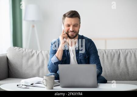Cheerful man freelancer working from home, using laptop Stock Photo