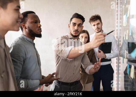 Businesspeople having meeting using sticky notes on glass wall Stock Photo