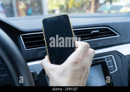 Hand of man holding cellphone in car interior. Vehicle mobile holder, equipment device concepts Stock Photo