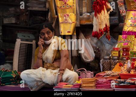Woman in stall  selling Indian spices talking on phone. Arguing, Mandai, Pune, Maharashtra, India