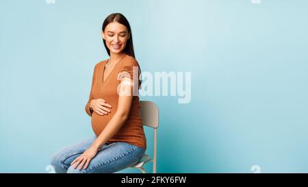 Pregnant Woman Vaccinated Against Coronavirus Sitting On Blue Background, Panorama Stock Photo
