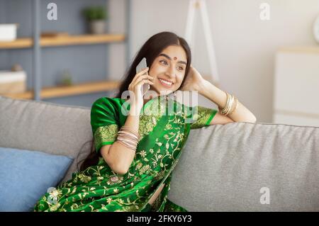 Beautiful smiling Indian woman in sari dress making phone call indoors Stock Photo
