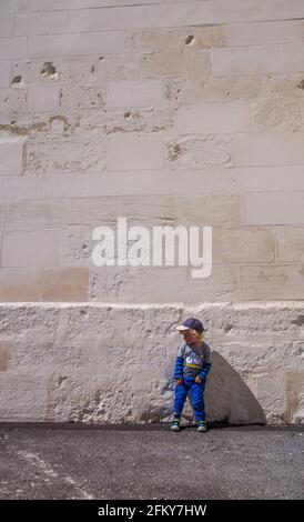 Young Blond hair boy stood against white wall Stock Photo