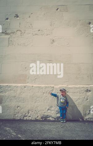 Young Blond hair boy stood against white wall Stock Photo