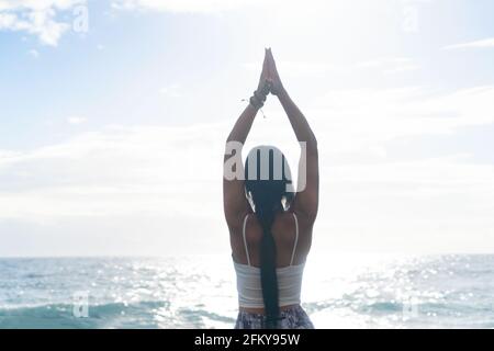 woman in sport clothes practicing yoga and meditating on beach in morning Stock Photo
