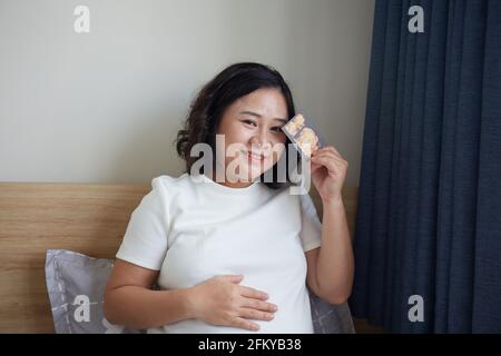 Young Vietnamese pregnant woman holding an ultrasound photo of her baby Stock Photo