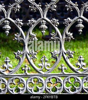 Background image of an old cemetery fence.  Fence is metal with an elaborate, silver colored design. Stock Photo