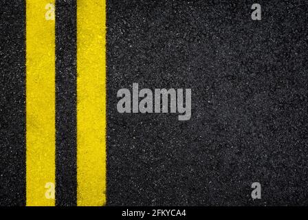 Top view of dark wet asphalt road with double yellow line. High resolution full frame textured background of black asphalt, viewed from above. Stock Photo