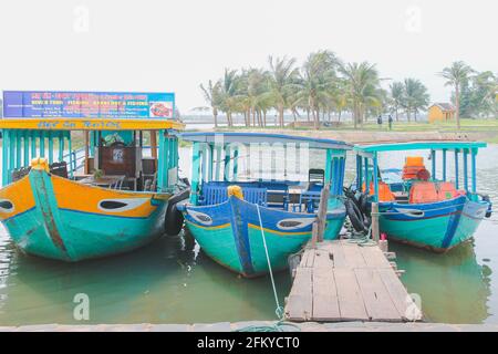 Hoi An, Vietnam - March 6 2019: Vibrant, colourful, traditional Vietnamese tour boats moored along the Thu Bon River in quaint, picturesque Hoi An, Vi Stock Photo