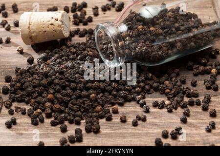 Piper nigrum - black peppercorns; photo on dark wooden background. Stock Photo