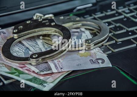 Handcuffs on paper money on keyboard in close-up Stock Photo