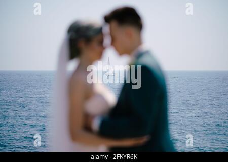 Silhouettes of hugging newlyweds on the background of a white sailing yacht in the open sea Stock Photo