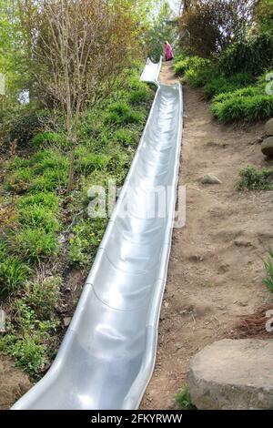 Long Slide, with bend half-way down, going down hill side Stock Photo