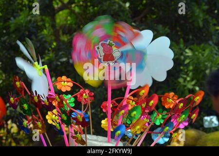 Colourful childrens wind spinners or pinwheel blowing in the wind. This group were for sale in a Chinese park on a sunny weekend. Stock Photo