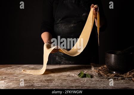 Lady standing behind table with pasta in hands Stock Photo
