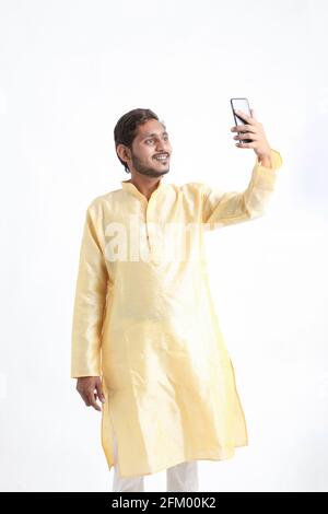 Indian man in traditional wear and taking selfie in smartphone Stock Photo