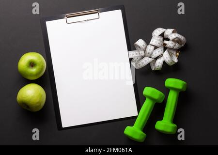 Fruits, dumbbells and blank sheet for your plan or goals. Sport, fitness and healthy lifestyle background. Top view flat lay with copy space Stock Photo