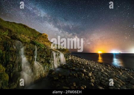 Osmington Mills, Dorset, UK.  5th May 2021.  UK Weather.   The Milky Way glows brightly in the clear night sky above a waterfall at the beach at Osmington Mills near Weymouth in Dorset.  Picture Credit: Graham Hunt/Alamy Live News Stock Photo
