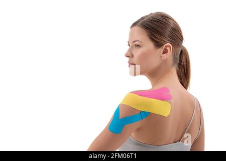 Colored kinesiotherapy tape on young sportswoman shoulder isolated on white background. Copy space Stock Photo