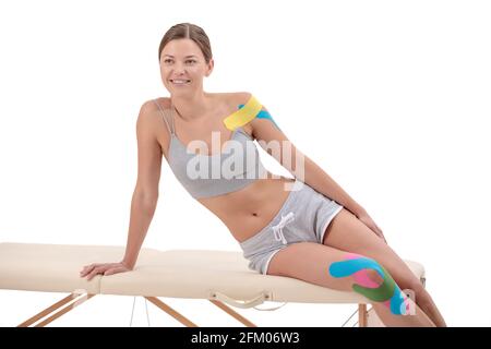 Kinesiology taping. Young female athlete isolated on white background with kinesiology tape on shoulder and knee. Fat lose, sport physical therapy Stock Photo