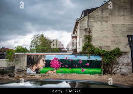 Ein Graffiti an einer alten Mauer zeigt ein Mädchen, welches wie bei einer Pusteblume ein Coronavirus anpustet, welches dann auseinander fliegt. Ein s Stock Photo