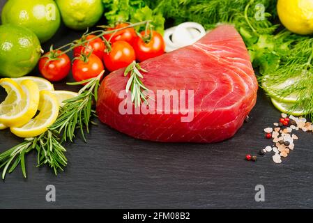 Tuna raw Steak, tuna sashimi, tuna fish sliced with vegetables. healthy eating with seafood, we cook at home. fish meat layout on black stone Stock Photo