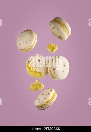 Different types of macaroons in motion falling on pink background Stock Photo