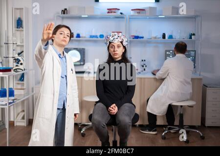 Researcher and patient with eeg headset looking at virtual display with touchscreen, virtual reality using medical inovation in neurological research lab. Scientists working with healthcare simulator. Stock Photo