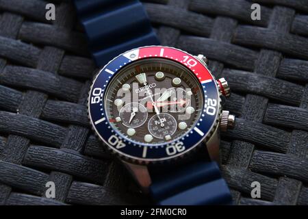 Closeup of a Seiko solar diver chronograph wrist watch on silicon band on a weaved garden table Stock Photo