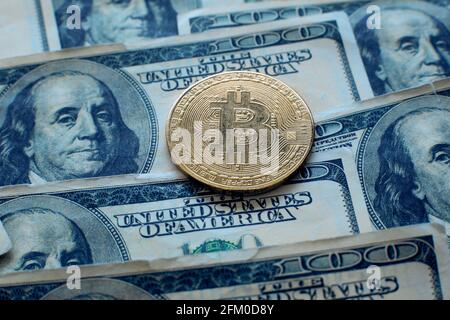 Bitcoin cryptocurrency coin lies on one hundred dollar bills Stock Photo