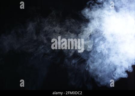 Illuminated smoke on black background in dark Stock Photo