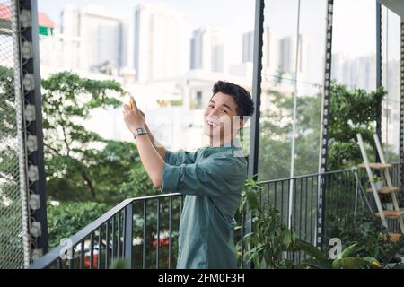 Young man takes photos with his phone of a beautiful view from the hotel's balcony Stock Photo