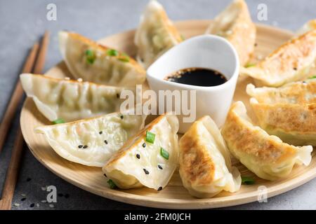 Gyoza or jiaozi fried stuffed dumplings on a bamboo plate, closeup view Stock Photo