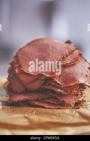 Fresh and delicious stack of sliced pastrami meat placed on wooden cutting board Stock Photo