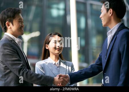 asian business associates meeting in the street in downtown financial district shaking hands Stock Photo