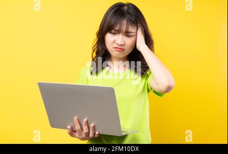 Young asian girl using laptop on yellow background Stock Photo